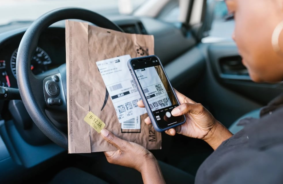Runner photographing a parcel label on her phone to send an update